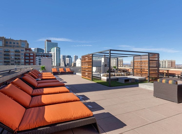 Rooftop Terrace Lounge with Cushioned Patio Armchairs Surrounded by Decorative Metal and Wood Partial Enclosure, Orange Cushioned Lounge Chairs with City View in the Background